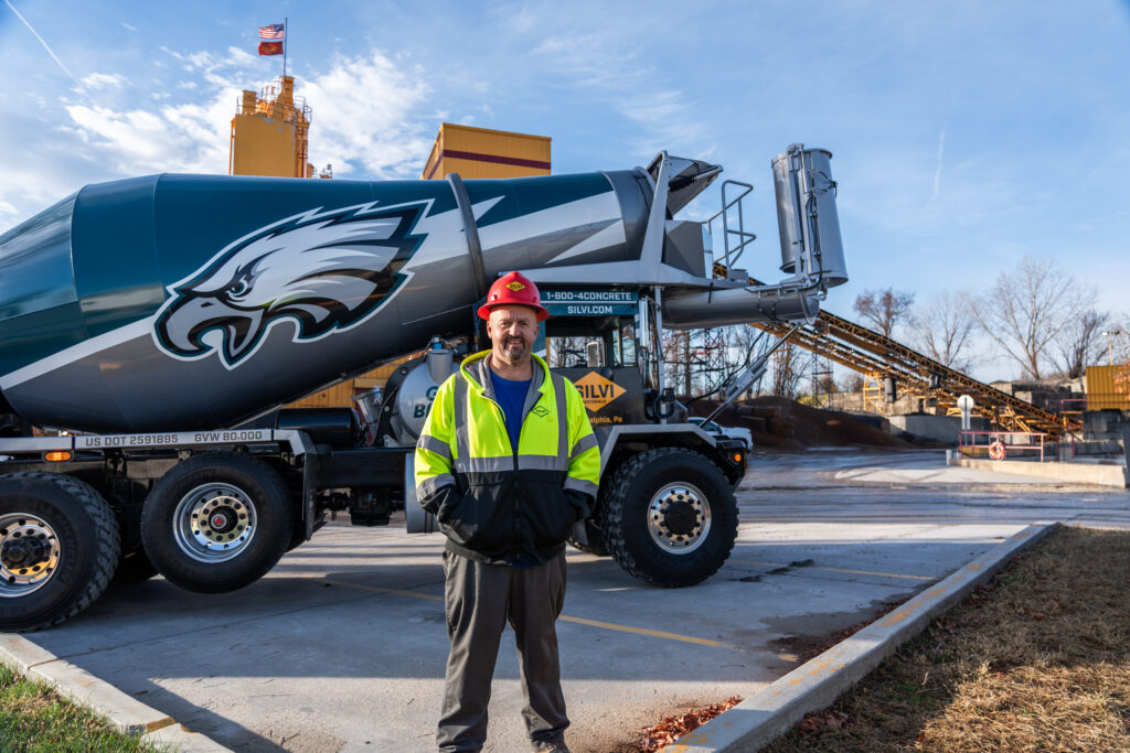 Silvi Materials' driver Michael Welsh standing in front of a concrete mixer. 